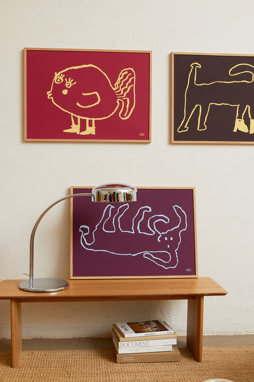 Framed burgundy print styled on a wooden sideboard in a modern interior