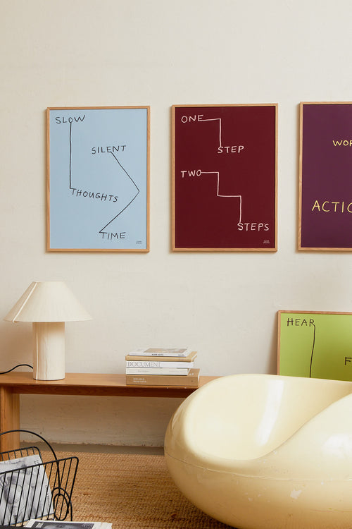 Blue framed art print styled above a wooden sideboard with decor objects