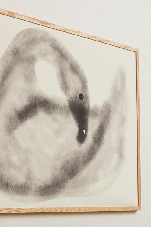 Art print with a stylized illustration of a swan in gray tones against a, with a soft and graphic expression. Styled in a minimalist interior.