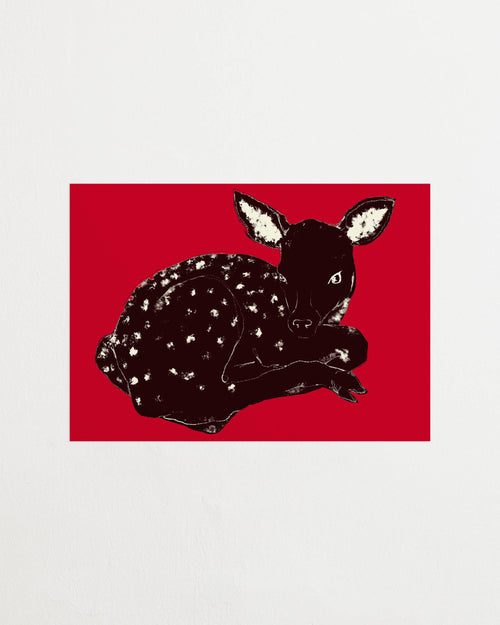Art print with a stylized illustration of a lying deer in a dark tone against a bright red background, with a minimalist and graphic expression. Styled in a minimalist interior.