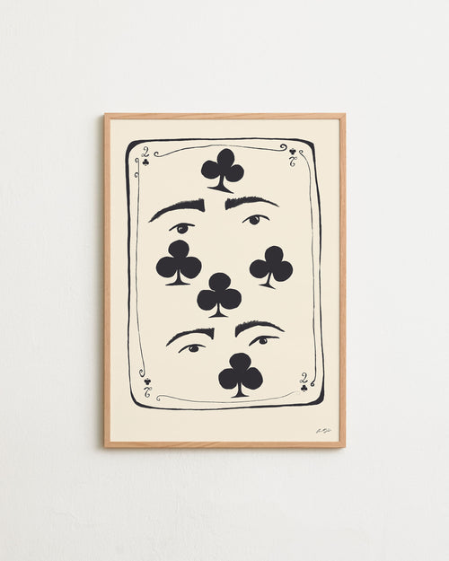 Framed artwork with playing card design featuring faces and clubs on a white wall.