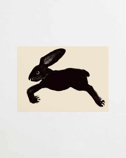Art print with a stylized illustration of a hare in a dark tone against an off-white background, with a minimalist and graphic expression. Styled in a minimalist interior.
