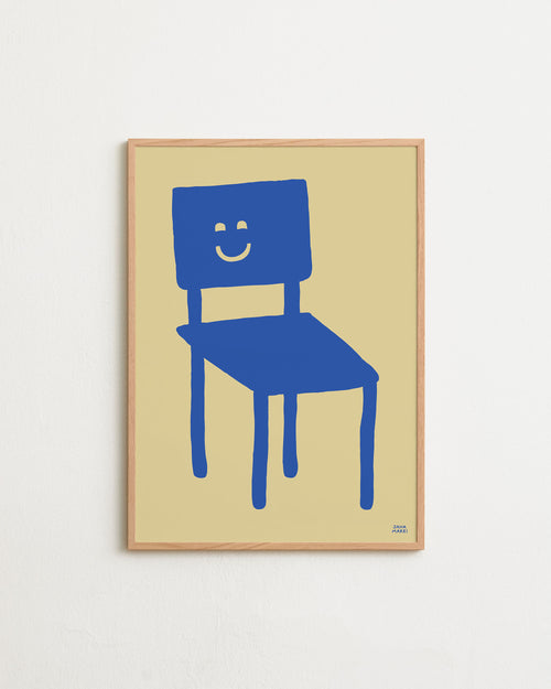 Framed artwork of a blue chair with a smiley face on a beige background