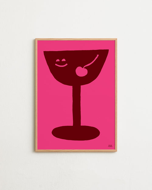 Framed artwork of a red cocktail glass with a cherry on a pink background
