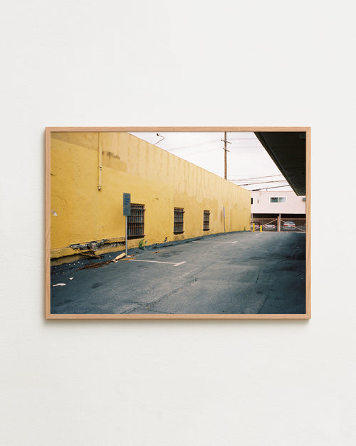Framed photograph of a yellow building and empty street on a white wall