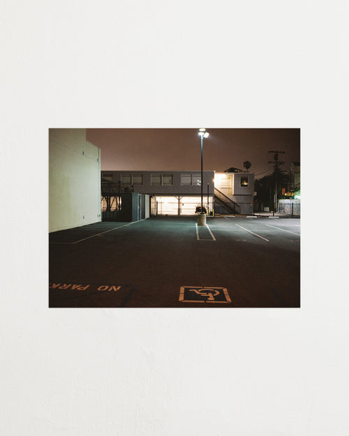 Empty parking lot at night with a building in the background